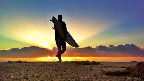 Silhouette of people standing on beach at sunset