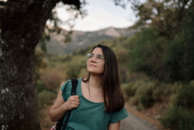 Portrait of young woman wearing sunglasses standing against trees