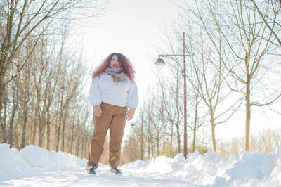 Full length of young woman standing on snow covered landscape
