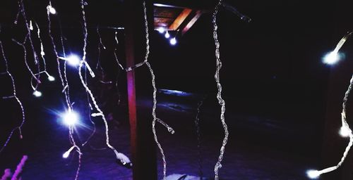 Low angle view of illuminated lighting equipment at night