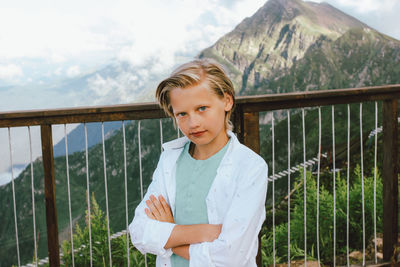 Portrait of smiling girl standing on railing against mountain