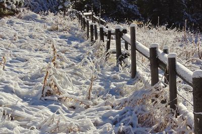 Snow covered wooden fence on field during winter
