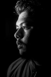 Close-up of thoughtful man against black background