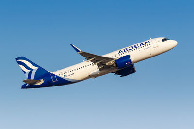 Low angle view of airplane flying against clear blue sky