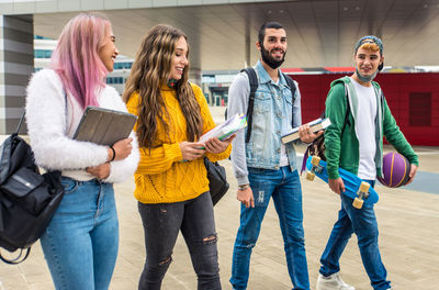 Cheerful friends carrying book outdoors