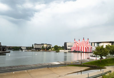 Scenic view of river by buildings against sky