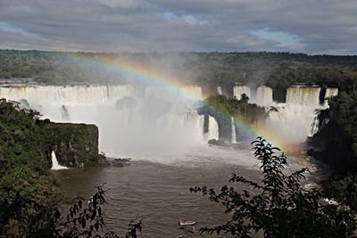 Scenic view of waterfall against cloudy sky
