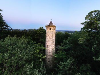 Low angle view of tower amidst trees and buildings against sky