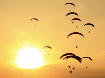 Low angle view of people flying against sky during sunset
