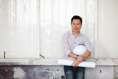 Portrait of smiling man standing against wall