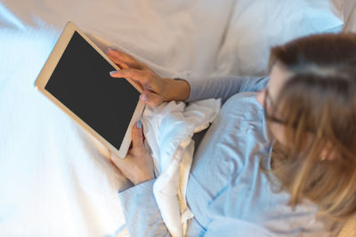 Close-up of woman using mobile phone while sitting on bed