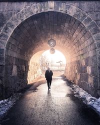 Rear view of man walking in tunnel