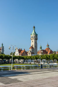 Street by buildings against clear blue sky