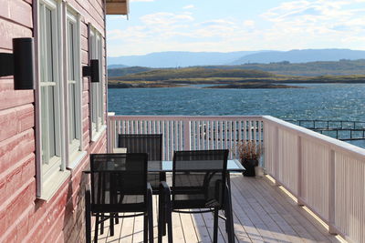 Chairs and table at balcony by lake