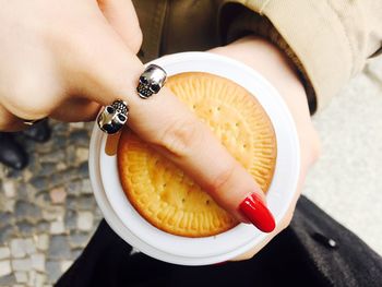 Cropped image of woman hand holding disposable cup with cookie