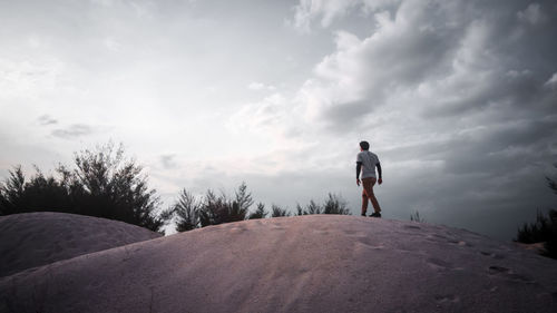 Full length of man standing on sand dune against sky