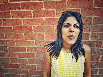 Portrait of woman standing against brick wall