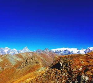 Scenic view of snowcapped mountains against clear blue sky