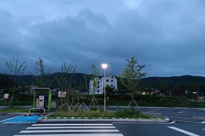 Street lights by road against sky in city