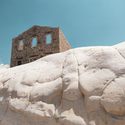 Low angle view of old building against blue sky and white stone