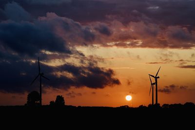 Silhouette of windmill against dramatic sky during sunset