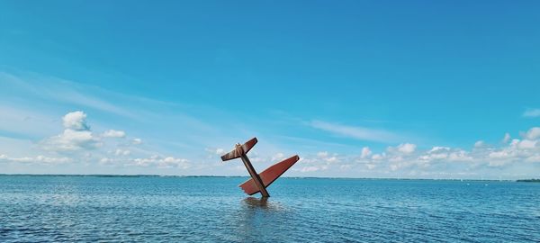 Woman in sea against blue sky