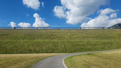 Panoramic view of road amidst field against sky