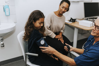 Doctor checking girls blood pressure