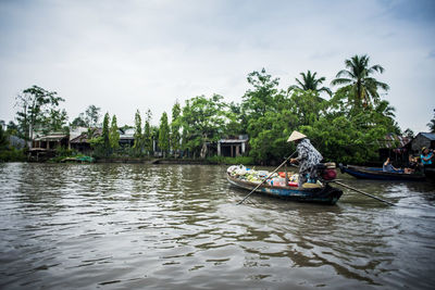 Man in river on boat against sky in vietnam