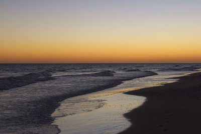 Scenic view of beach against clear sky during sunset