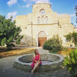 Woman sitting against building