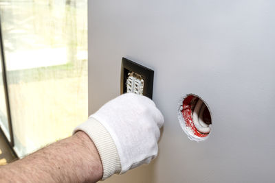 Close-up of man hand against white wall at home