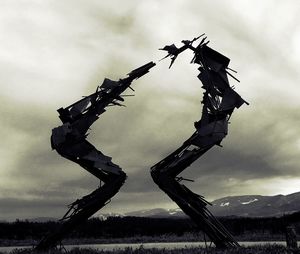 Low angle view of silhouette cranes on field against sky