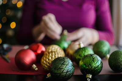 Midsection of woman preparing baubles on table