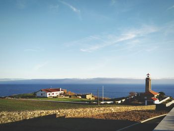 Lighthouse by sea against sky