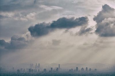 View of cityscape against cloudy sky