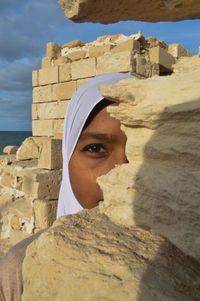 Portrait of one eyed woman behind rock