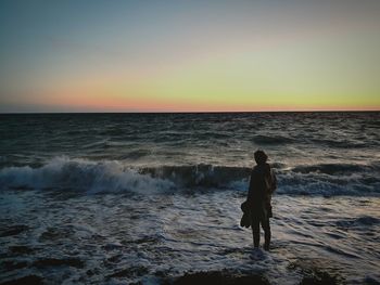 Man standing on beach against sky during sunset