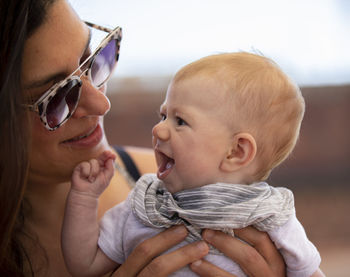 Woman carrying daughter against sky