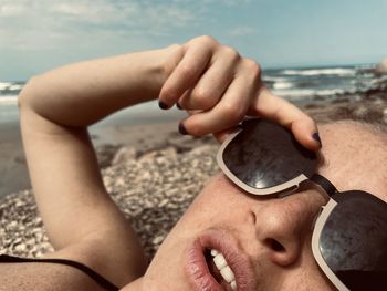 Low section of woman wearing sunglasses at beach