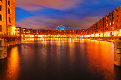 Illuminated bridge over river against sky at sunset