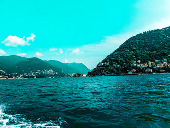 Scenic view of sea and mountains against blue sky