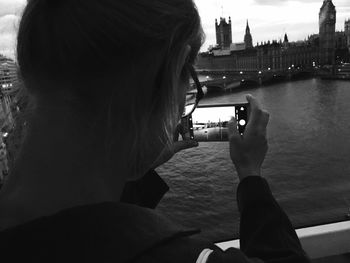 Rear view of woman photographing river