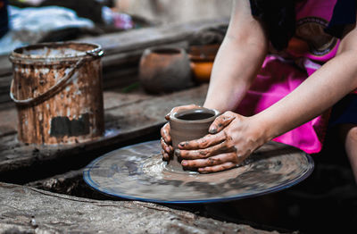 Midsection of woman molding shape on pottery wheel