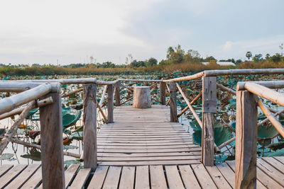 Wooden footbridge on pier against sky