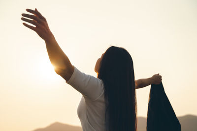 Low angle view of silhouette woman standing against sky during sunset