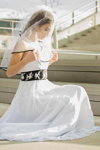 Side view of bride woman in veil posing on boardwalk