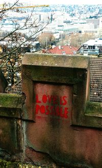 Text on wall against buildings in city