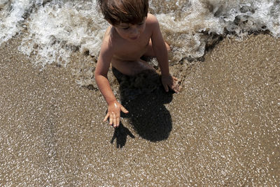 High angle view of boy playing on sand at beach