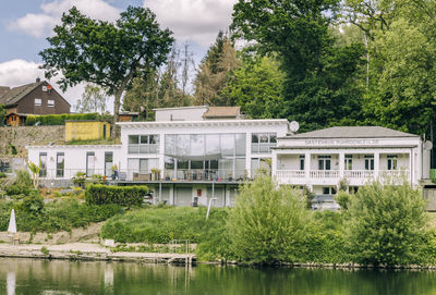 Houses by river and trees against sky